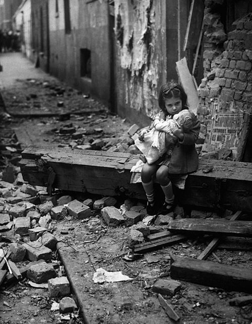 An English girl comforts her doll in the rubble of her bomb-damaged home in 1940