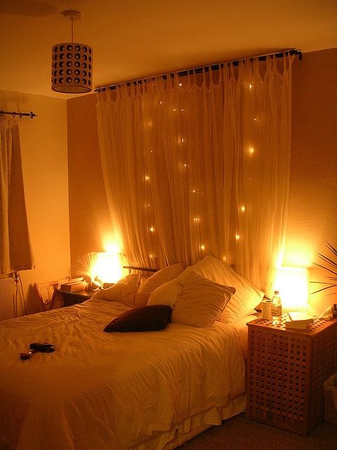Hang a curtain behind a bed with string lights -very simple and pretty