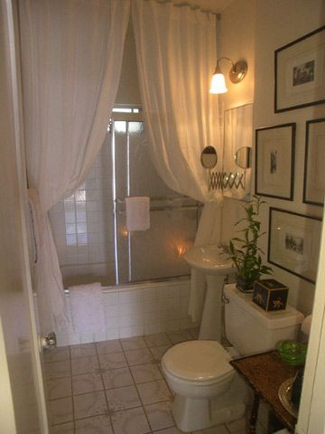 small bathroom made fancy with floor to ceiling curtains in front of shower door