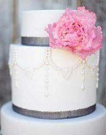gray ribbon and pink flower on wedding cake