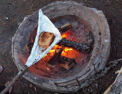 making grilled ham and cheese while camping using a stick and aluminum foil