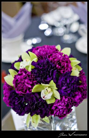 purple and green centerpiece of carnations and orchids