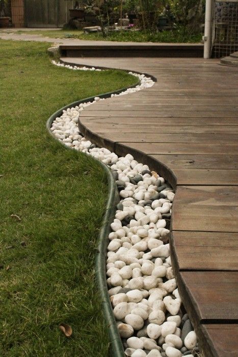 Use rocks to separate the grass from the deck, then bury rope lights in the rock