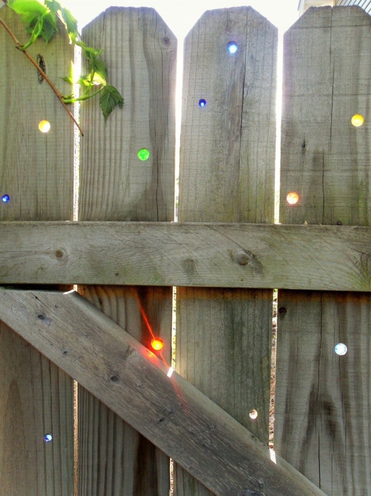 Drill holes in your fence and put marbles in the holes.  A kaleidoscope of color