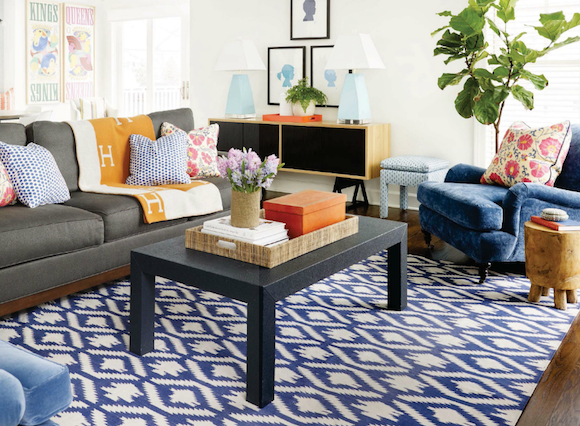 grey couch with navy graphic rug, blue chairs, pops of orange, black coffee tabl