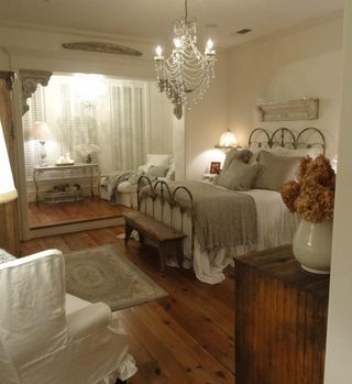 Bedroom with white walls, spread, slipcovers, taupe pillows, blanket, small area