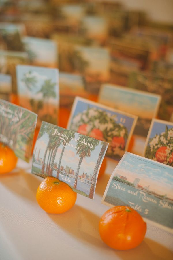 Oranges holding vintage postcard escort cards.