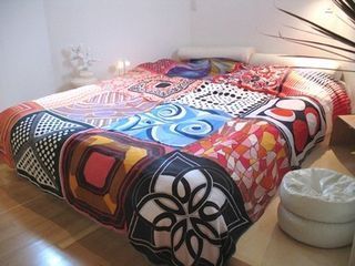 This bedcover is made of square silk scarves simply sewn together.