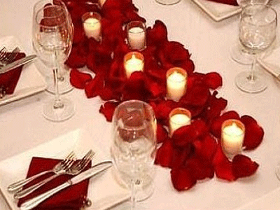 Beautiful tablescape. Simple white with red rose petals intersperced with Candle