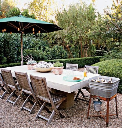 gravel patio. teak folding chairs. concrete table? old wash tub as ice bucket/co