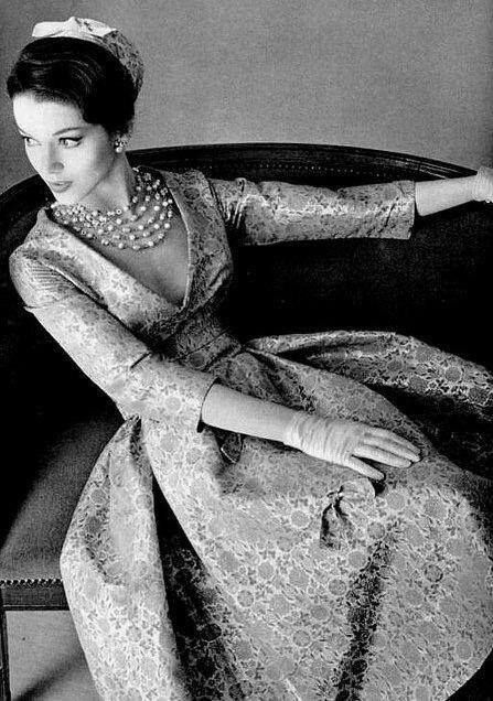 1957 Model is wearing a gold leaf brocade dress with a deep decolletage by Jean