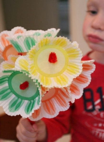 A child holding a bouquet of flowers made of cupcake liners