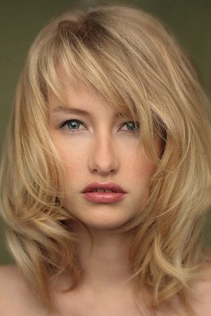 Medium length wavy layered blonde with side swept wispy bangs hairstyle