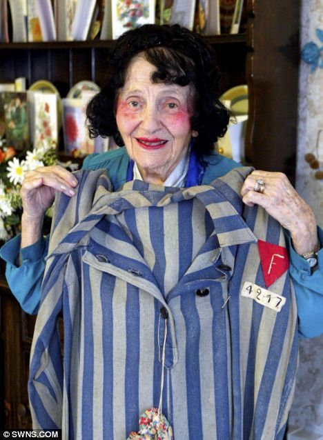 A 104-year-old Holocaust survivor holds up the concentration camp uniform she us