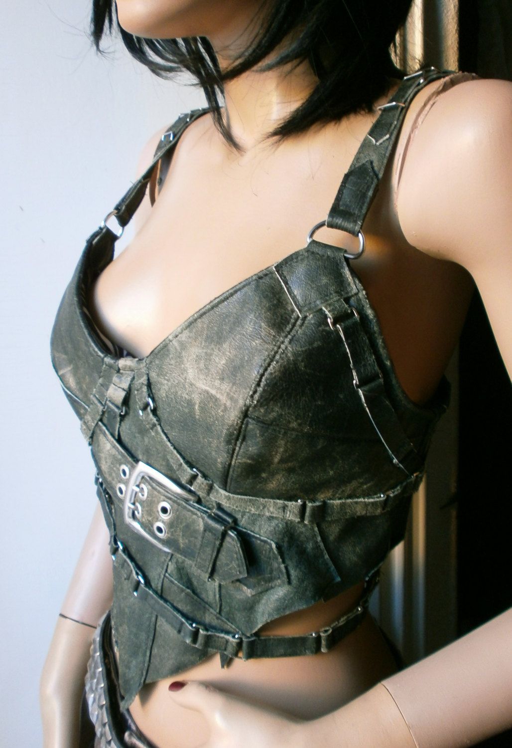 Worn out green leather corset top with buckles and straps all over. 115.00, via