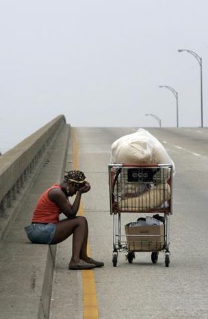 Kimi Seymour, 27, of New Orleans, takes a break along Interstate 10 as she walked along the highway on Sept. 1, 2005. Seymour was displaced from her New Orleans home by Hurricane Katrina. This photo