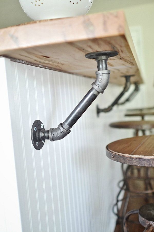 Industrial pipes holding up a solid wood bar in the kitchen.