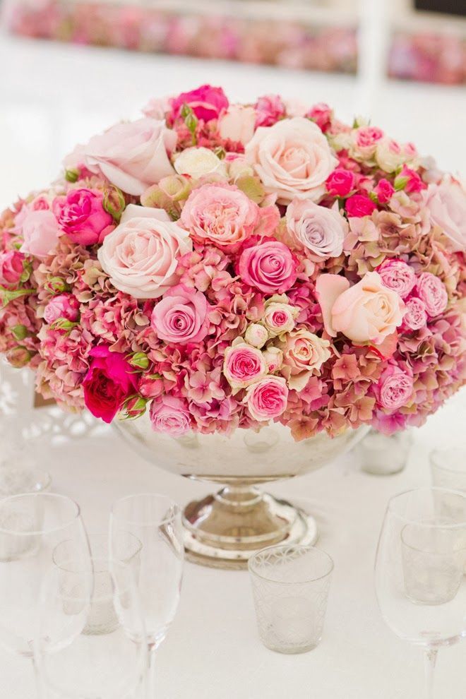 Low flower arrangement in shades of pink with a variety of roses for the wedding reception