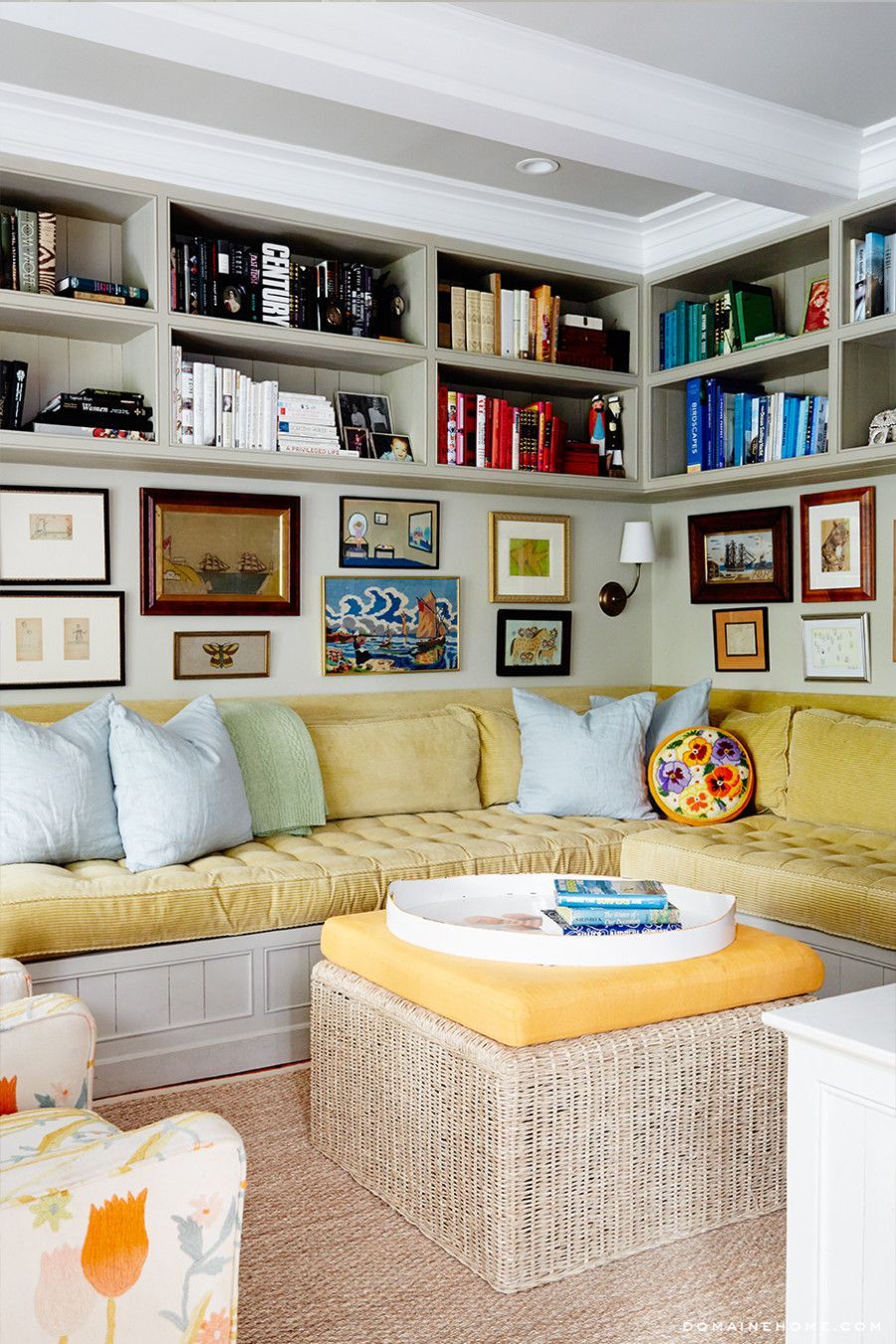 Coastal family room – sag habor – built-in seating area. Bookshelves up to the ceiling with books arranged by color, gallery wall