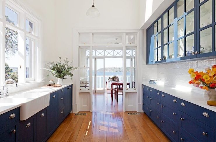 Cobalt blue glass-front kitchen cabinets, marble countertops, white glass subway tiles backsplash, farmhouse sink and lots and
