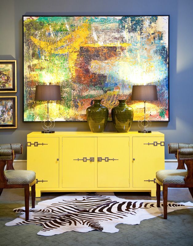 Bright yellow cabinet console with abstract art, modern lamps, zebra hide rug in a grey room – Via: Gary Riggs Home