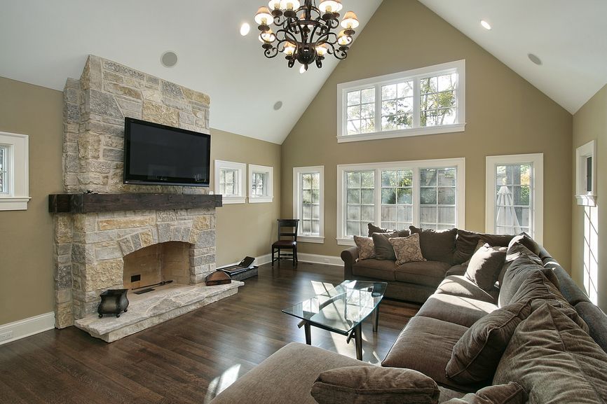 Family room style with hard wood floor, large sectional sofa, television mounted above brick fireplace with white cathedral