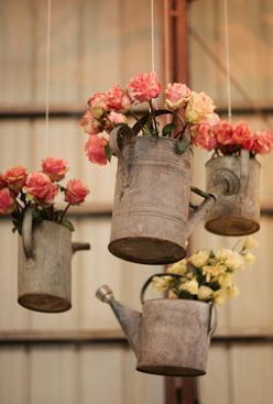 Hanging old watering cans with flowers.  Adaptable for any season.