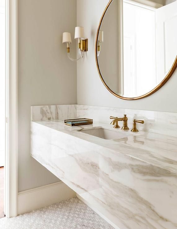 Chic bathroom boasts a grey and white marble floating vanity sink, suspended over a marble mosaic …