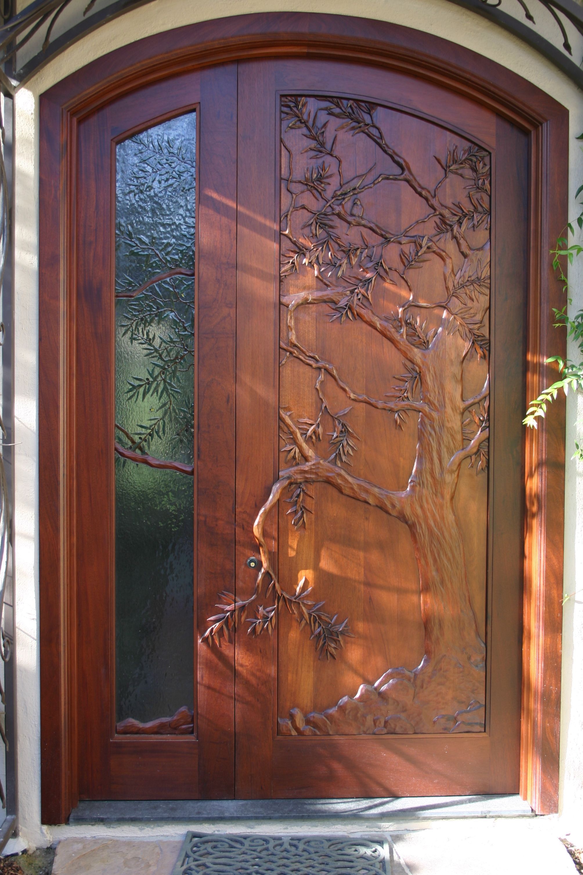 Hand carved door, olive tree carved in wood and theme continued in art glass side lite. David Frisk