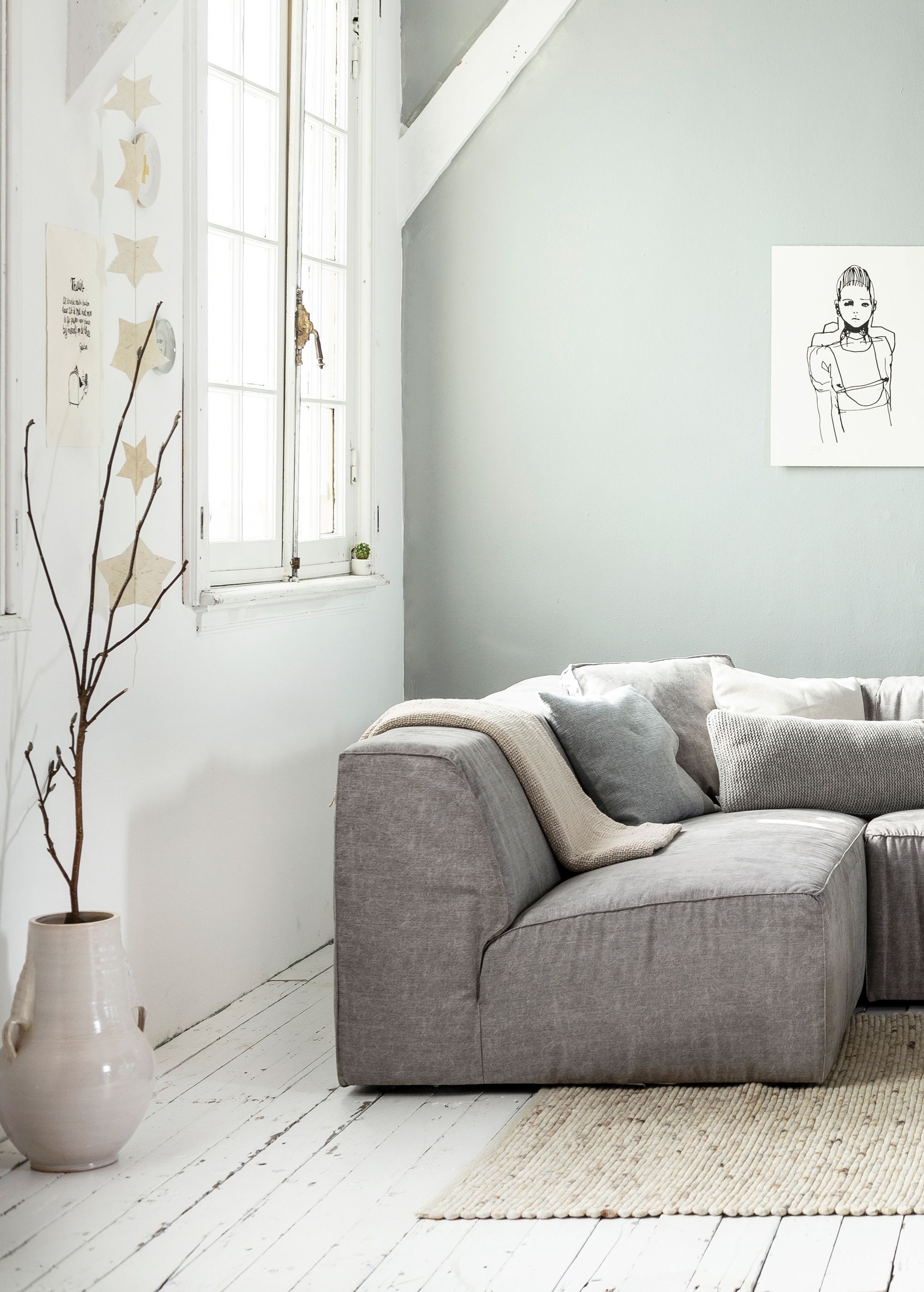 White, grey and light interior / living room with white wooden floors and a grey wall, grey canvas vtwonen couch Lazy, a big