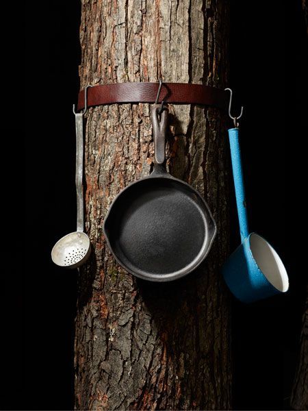 Camping storage: An old leather belt around a tree, with S-hooks to hang utensil